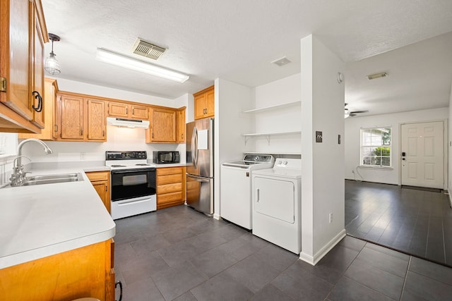 kitchen with range with electric cooktop, stainless steel refrigerator, a sink, under cabinet range hood, and washer and clothes dryer