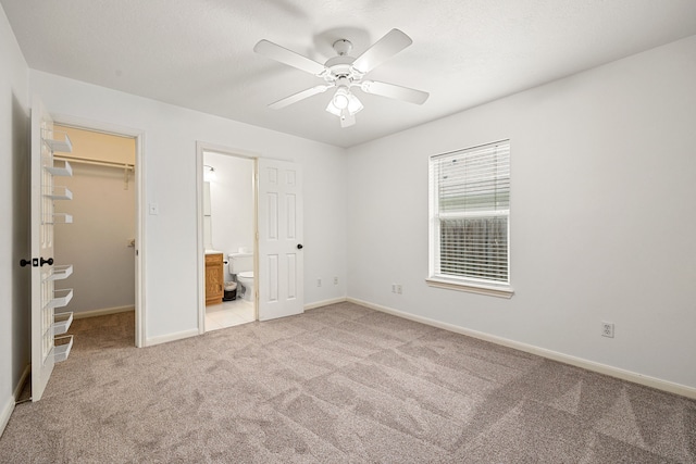 unfurnished bedroom with carpet floors, baseboards, ensuite bathroom, a spacious closet, and a closet