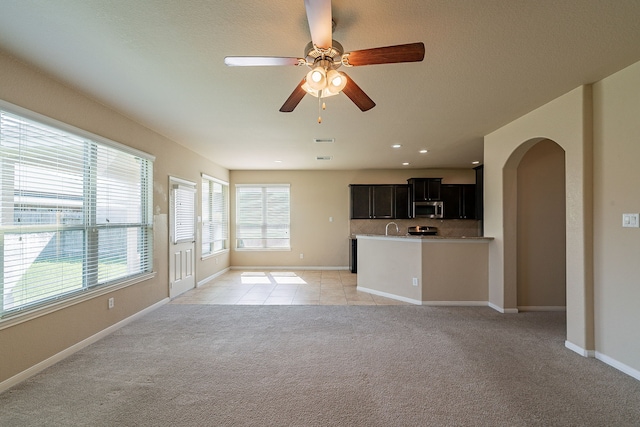 18922 Deer Trace Dr, Crosby, TX 77532 - unfurnished living room featuring arched walkways, baseboards, light colored carpet, ceiling fan, and light tile patterned floors