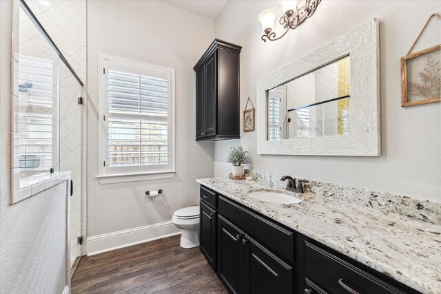 full bathroom with baseboards, wood finished floors, a stall shower, and vanity