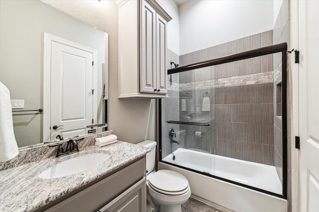 bathroom with vanity, bath / shower combo with glass door, and toilet