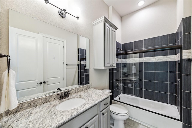 bathroom featuring toilet, bath / shower combo with glass door, and vanity