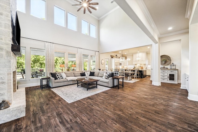 living area featuring ornamental molding, ceiling fan with notable chandelier, and wood finished floors