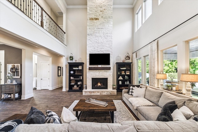 living area with a healthy amount of sunlight, baseboards, a fireplace, and a towering ceiling