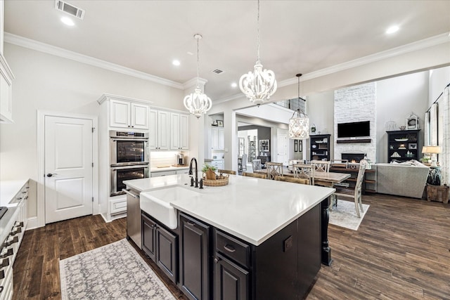 kitchen featuring a stone fireplace, visible vents, a sink, a chandelier, and stainless steel appliances