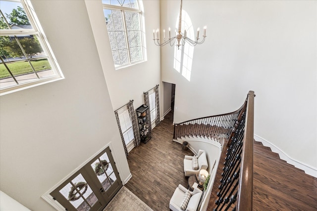 entrance foyer with an inviting chandelier, a healthy amount of sunlight, wood finished floors, and a towering ceiling
