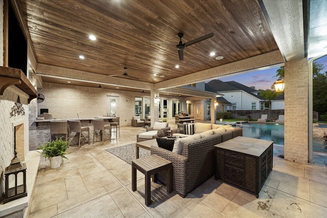 view of patio with ceiling fan, an outdoor hangout area, outdoor dry bar, a fenced in pool, and exterior kitchen