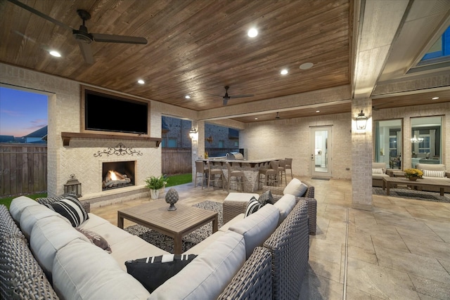 living room with ceiling fan, wooden ceiling, and a large fireplace