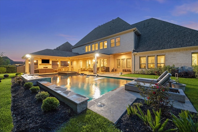 rear view of property featuring a patio, outdoor lounge area, an outdoor pool, and an outdoor kitchen