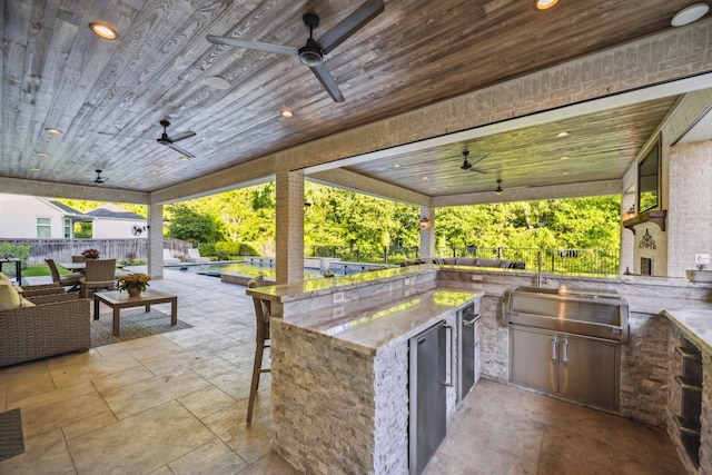 view of patio featuring fence, outdoor wet bar, ceiling fan, and area for grilling