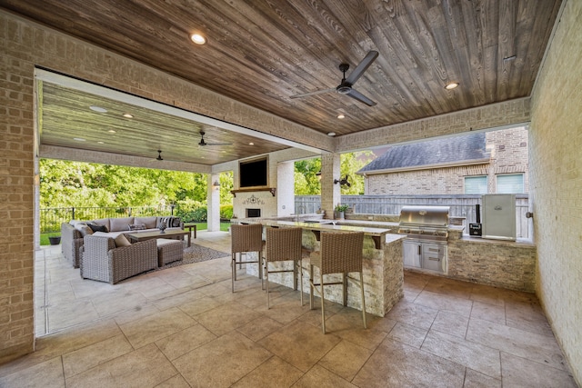 view of patio featuring fence, an outdoor living space with a fireplace, exterior kitchen, ceiling fan, and a grill