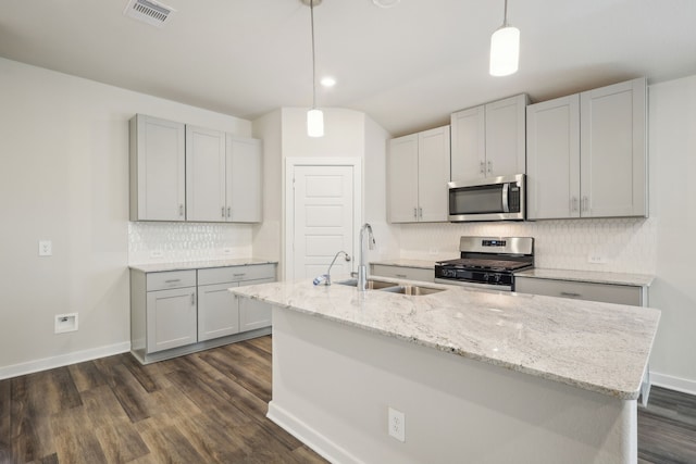 7746 Beaufort Ln, Baytown, TX 77523 - kitchen with appliances with stainless steel finishes, a sink, dark wood-style floors, tasteful backsplash, and a kitchen island with sink