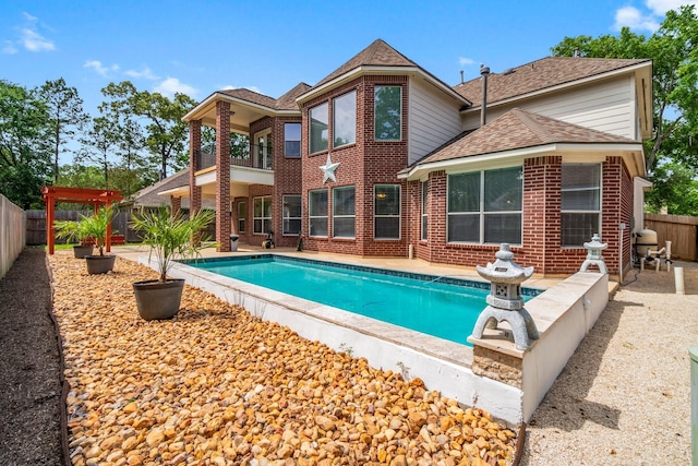 20960 Sweetwood Cir, Porter, TX 77365 - back of house with a fenced in pool, a fenced backyard, a patio area, a shingled roof, and a balcony