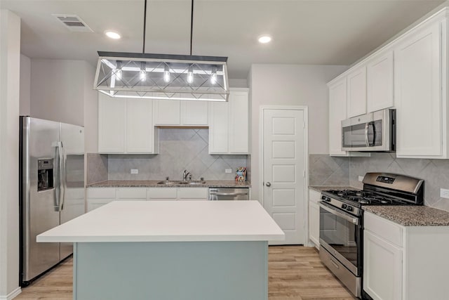 438 Camas Creek Ln, Magnolia, TX 77354 - kitchen with a sink, white cabinetry, light wood-type flooring, and appliances with stainless steel finishes