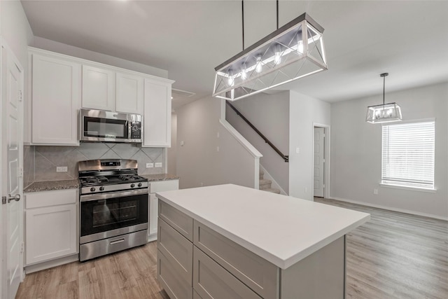 438 Camas Creek Ln, Magnolia, TX 77354 - kitchen featuring a center island, white cabinetry, light wood-type flooring, appliances with stainless steel finishes, and decorative backsplash