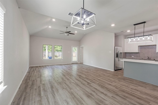 438 Camas Creek Ln, Magnolia, TX 77354 - unfurnished living room with light wood-style floors, recessed lighting, and ceiling fan with notable chandelier