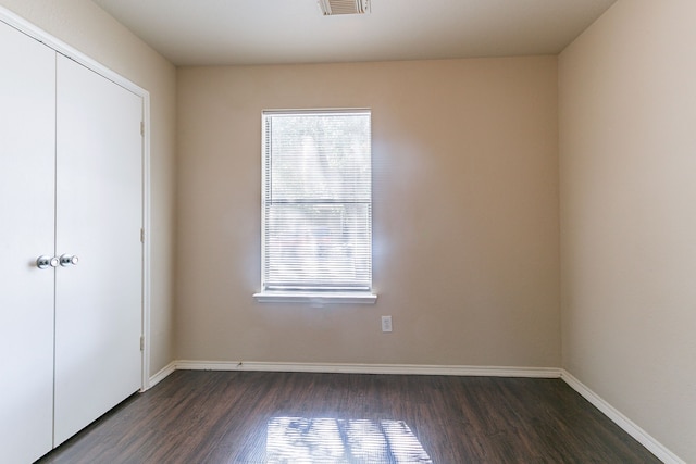 unfurnished bedroom featuring baseboards, visible vents, and dark wood-style floors