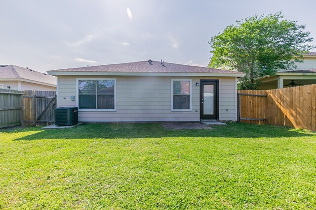 rear view of property with a fenced backyard, central AC unit, and a yard