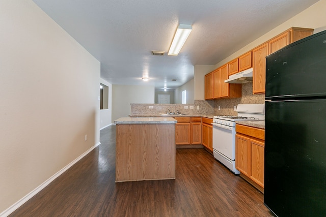 kitchen featuring white range with gas stovetop, visible vents, under cabinet range hood, dark wood-style floors, and freestanding refrigerator