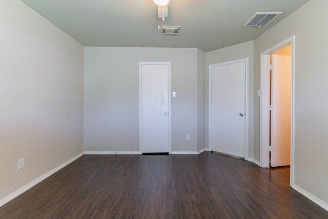 spare room with baseboards, dark wood-type flooring, and visible vents