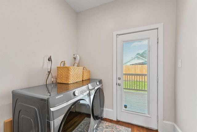 clothes washing area featuring baseboards, wood finished floors, laundry area, and washer and clothes dryer