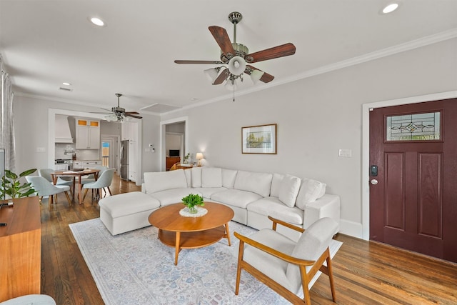 living room featuring wood finished floors, ceiling fan, baseboards, ornamental molding, and recessed lighting
