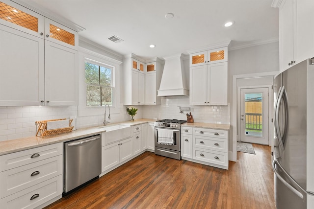 kitchen featuring stainless steel appliances, a sink, white cabinetry, ornamental molding, and premium range hood