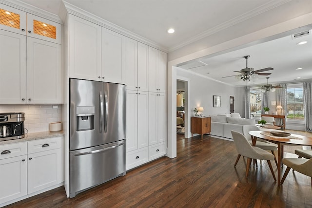 kitchen with dark wood-style floors, stainless steel fridge, visible vents, a ceiling fan, and ornamental molding