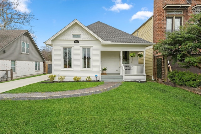 view of front of home with roof with shingles, a front yard, and covered porch