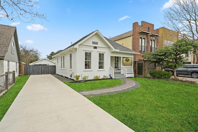 view of front facade with concrete driveway, a front lawn, fence, a porch, and roof with shingles