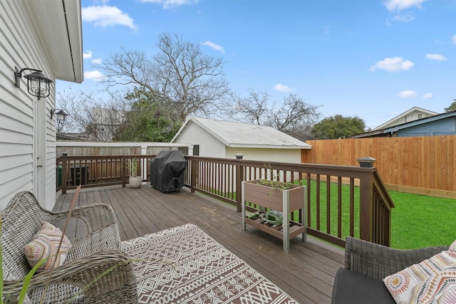 deck featuring fence, an outbuilding, a yard, and area for grilling