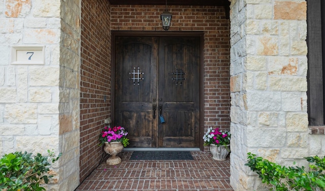 view of exterior entry with stone siding and brick siding