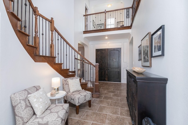foyer with arched walkways, a high ceiling, and stairway