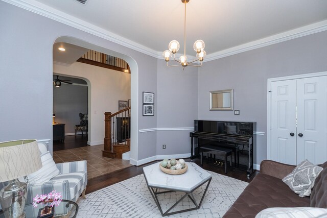 living room featuring crown molding, stairs, baseboards, a chandelier, and arched walkways