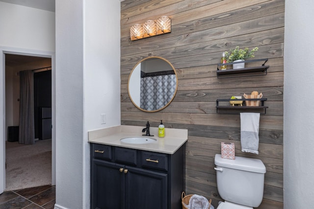 bathroom featuring wooden walls, toilet, and vanity