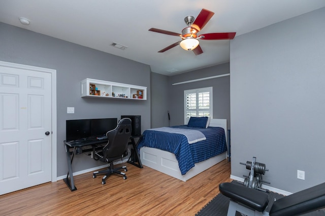 bedroom with visible vents, a ceiling fan, baseboards, and wood finished floors