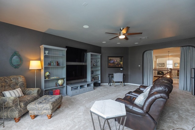 carpeted living room with arched walkways and a ceiling fan
