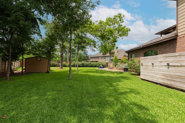 view of yard with a storage shed, fence, and an outdoor structure