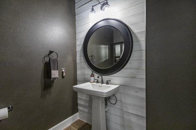 bathroom with wood walls and tile patterned floors