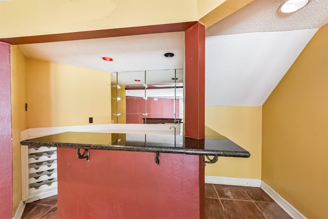 9402 Stockport Dr, Spring, TX 77379 - kitchen with a kitchen bar, baseboards, dark stone counters, and dark tile patterned flooring