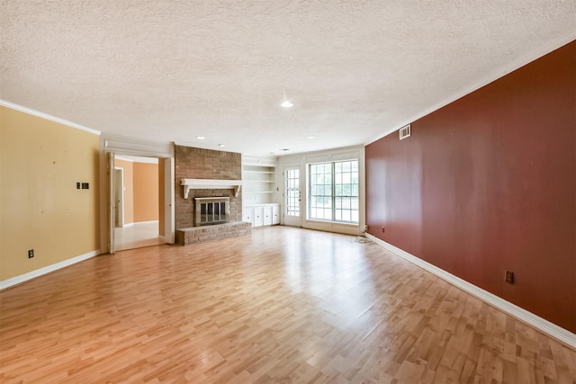 9402 Stockport Dr, Spring, TX 77379 - unfurnished living room with a textured ceiling, light wood-style floors, baseboards, crown molding, and built in shelves