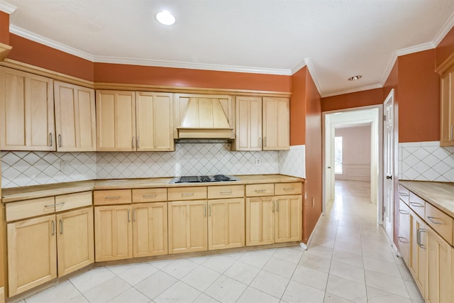 9402 Stockport Dr, Spring, TX 77379 - kitchen with custom range hood, light brown cabinets, stovetop with downdraft, backsplash, and ornamental molding