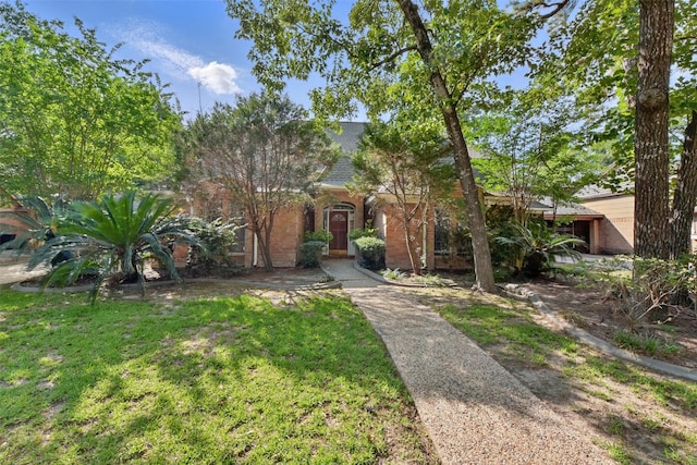 9402 Stockport Dr, Spring, TX 77379 - view of property hidden behind natural elements with a front yard, brick siding, and roof with shingles