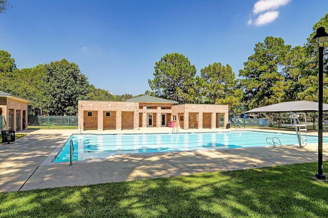 community pool with a patio, a lawn, and fence