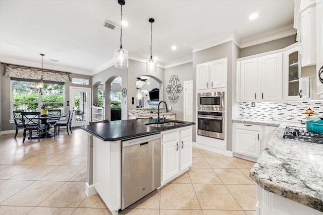 kitchen featuring a sink, appliances with stainless steel finishes, light tile patterned floors, and arched walkways