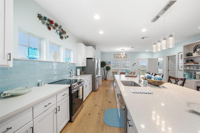 kitchen with white cabinets, a sink, pendant lighting, tasteful backsplash, and appliances with stainless steel finishes