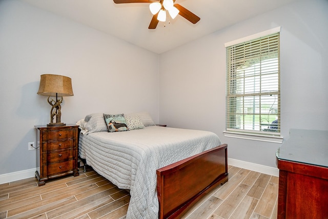 bedroom with a ceiling fan, wood finish floors, and baseboards