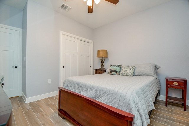 bedroom featuring ceiling fan, baseboards, wood tiled floor, visible vents, and a closet