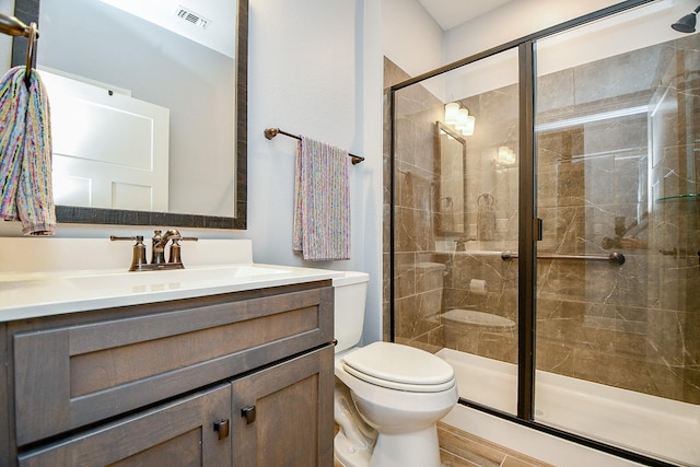 full bathroom with vanity, a shower stall, toilet, and visible vents
