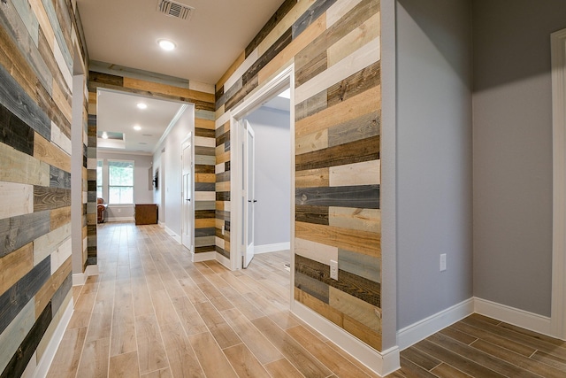 corridor featuring wooden walls, recessed lighting, baseboards, wood finished floors, and visible vents